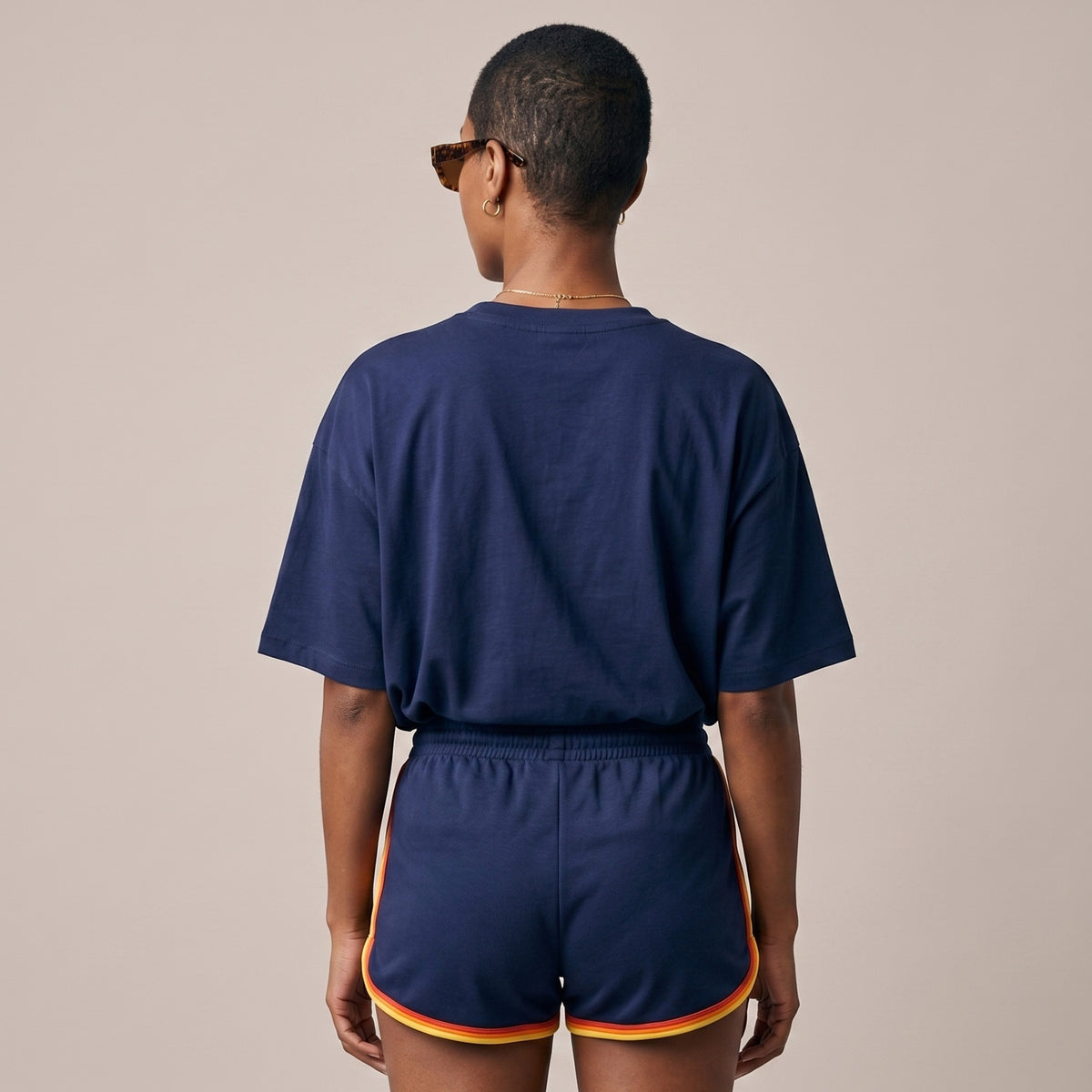 Person wearing a navy blue outfit with shorts on a beige background