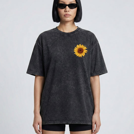 Person wearing a black t-shirt with a sunflower design on a plain background