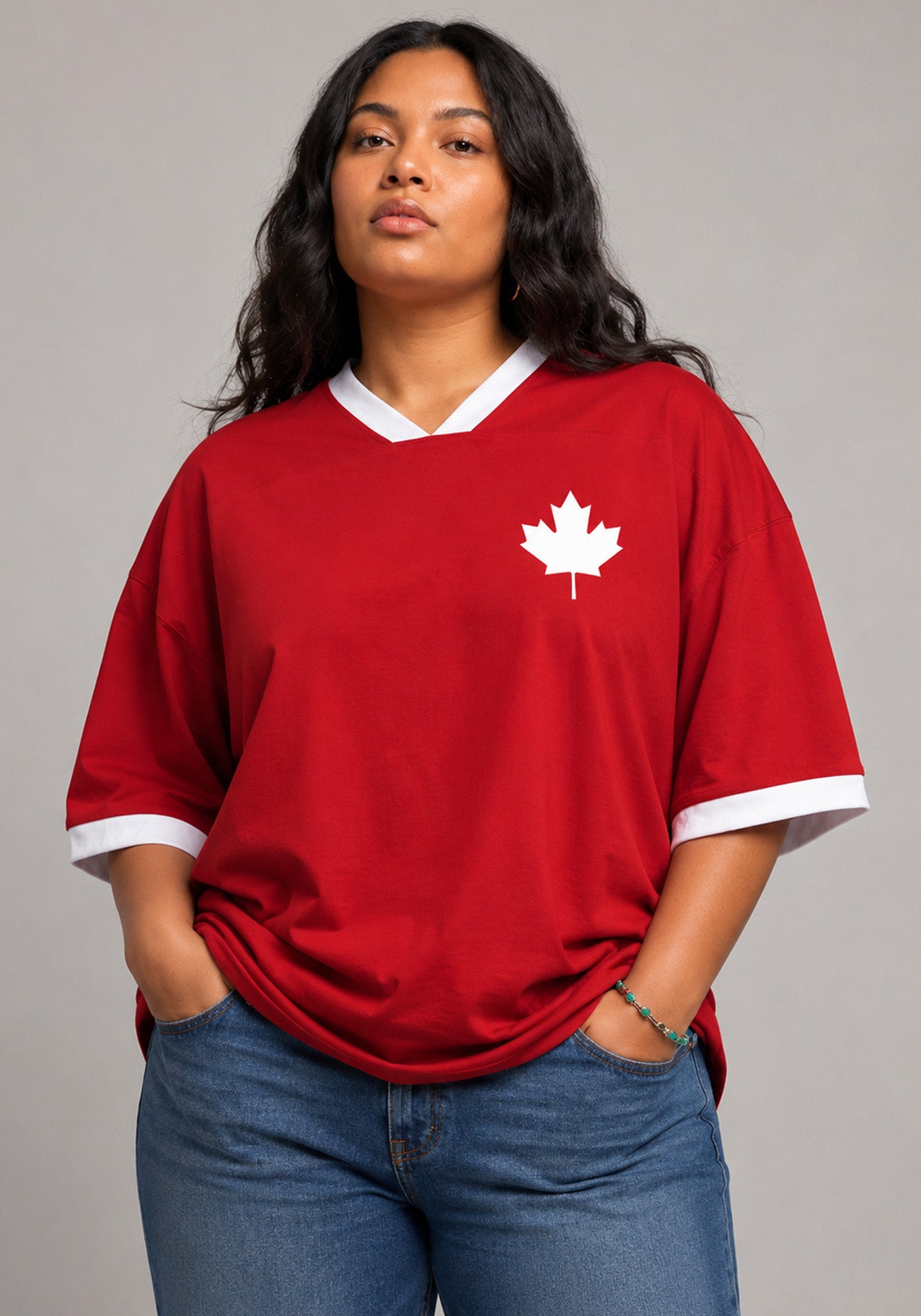 High-end editorial studio portrait of a woman wearing an oversized red V-neck jersey with a white maple leaf emblem and natural skin textures.