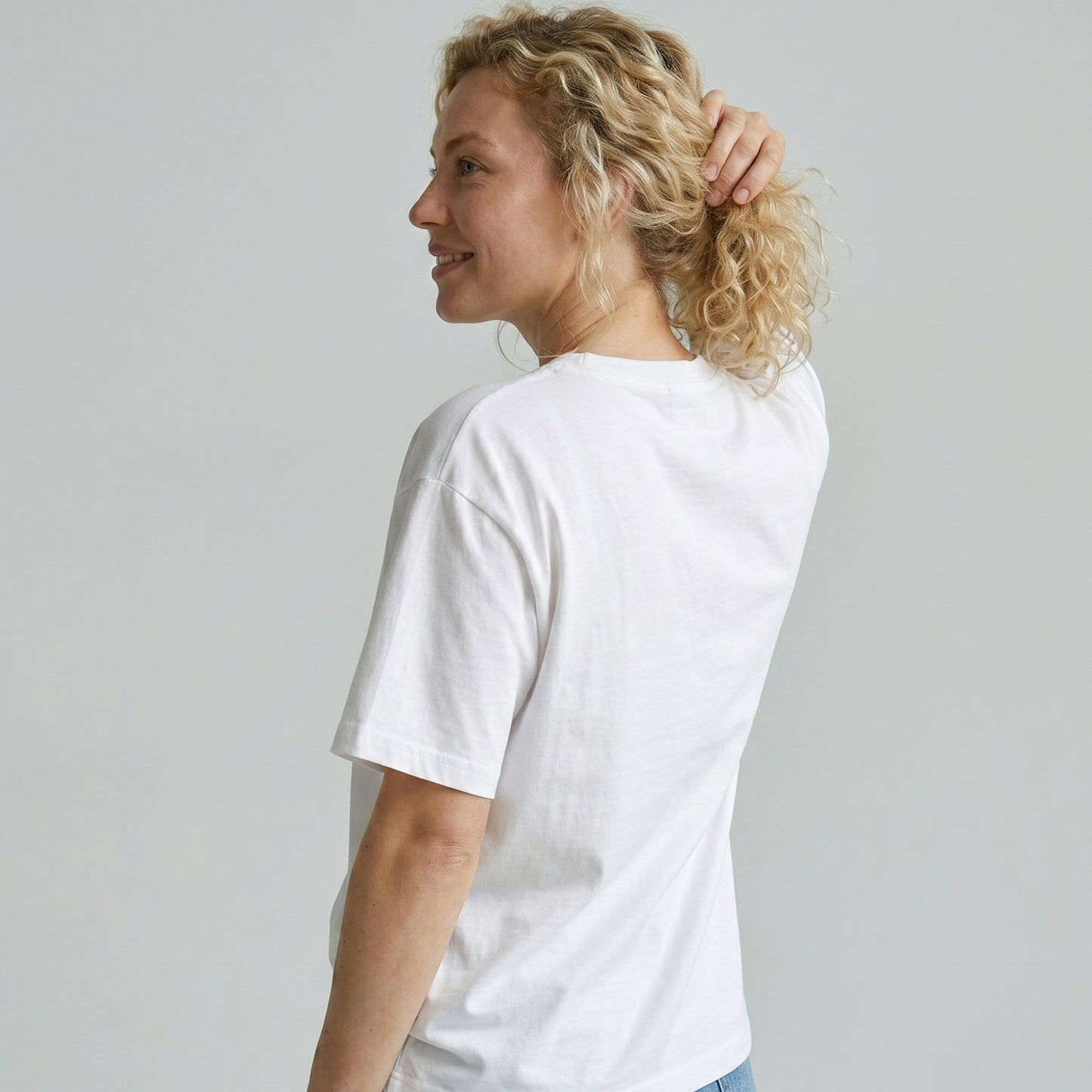 Woman wearing a plain white t-shirt against a light gray background