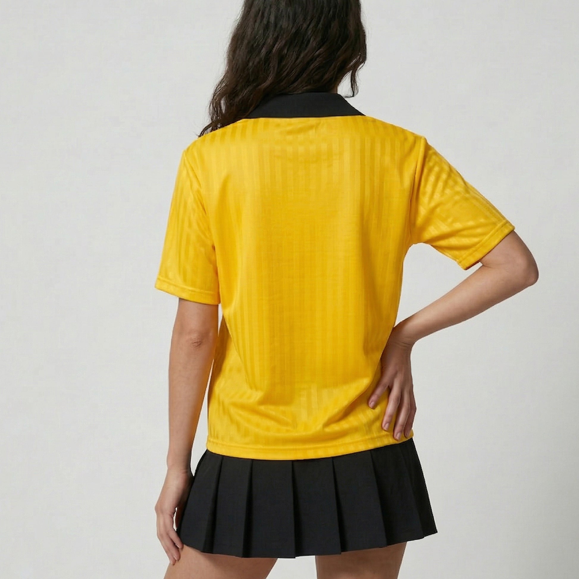 Person wearing a yellow shirt and black skirt on a plain background
