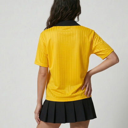 Person wearing a yellow shirt and black skirt on a plain background