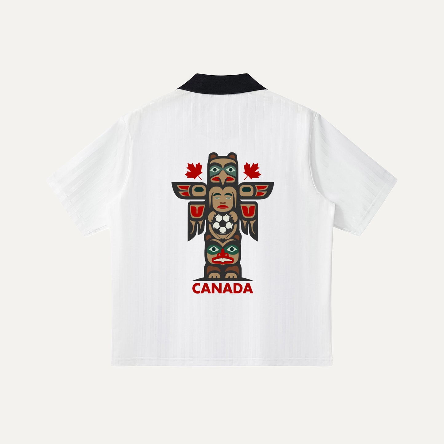 The back of a white soccer jersey showcasing a large, colorful Indigenous-inspired totem pole graphic in the center, with the word "CANADA" and two small red maple leaves printed in red below it.
