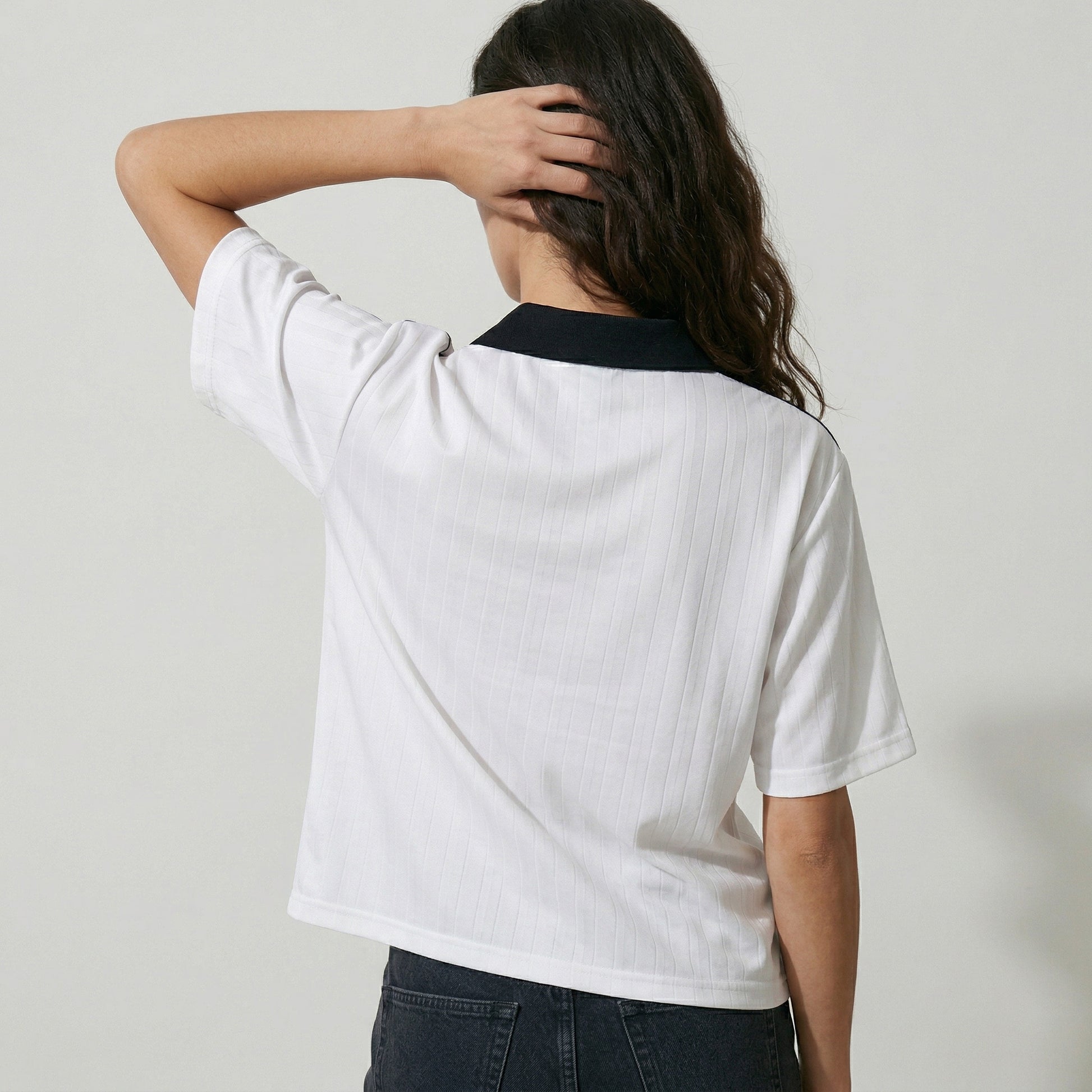 Person wearing a white t-shirt with a black collar against a plain background