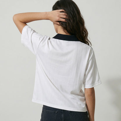Person wearing a white t-shirt with a black collar against a plain background