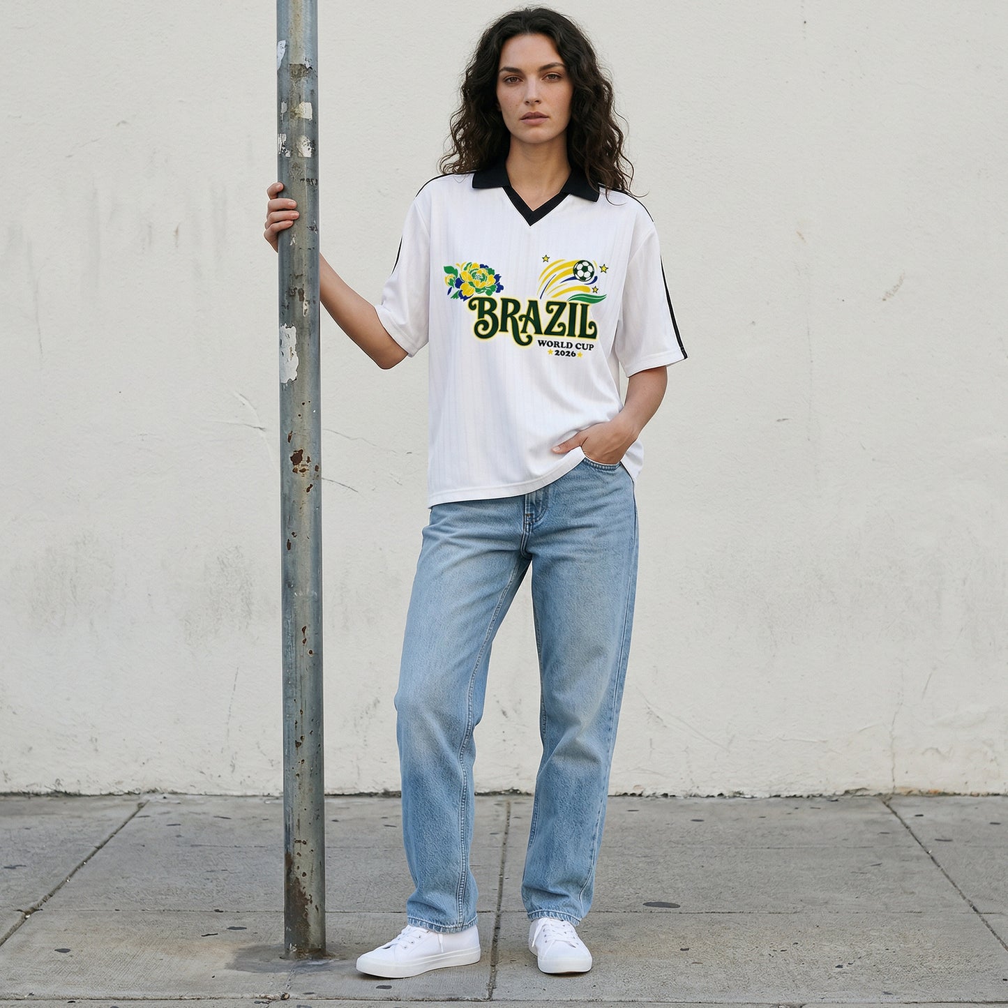 Woman wearing a Brazil World Cup t-shirt and jeans standing against a plain wall.