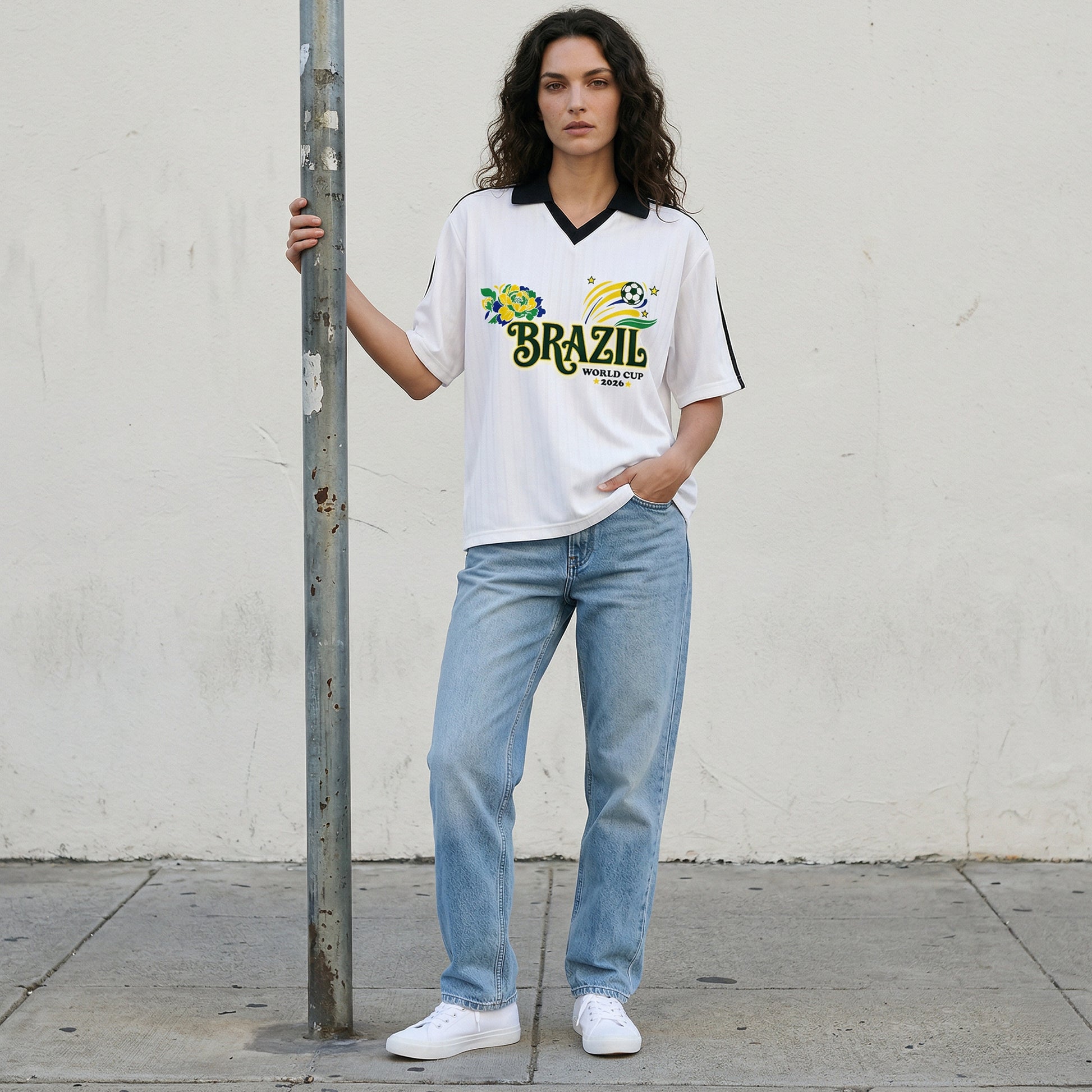 Woman wearing a Brazil World Cup t-shirt and jeans standing against a plain wall.