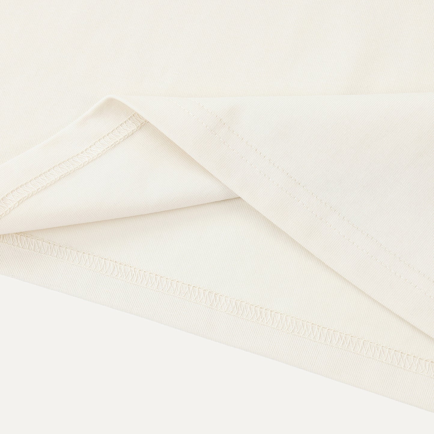 Close-up of a folded white fabric with a subtle texture on a light beige background.