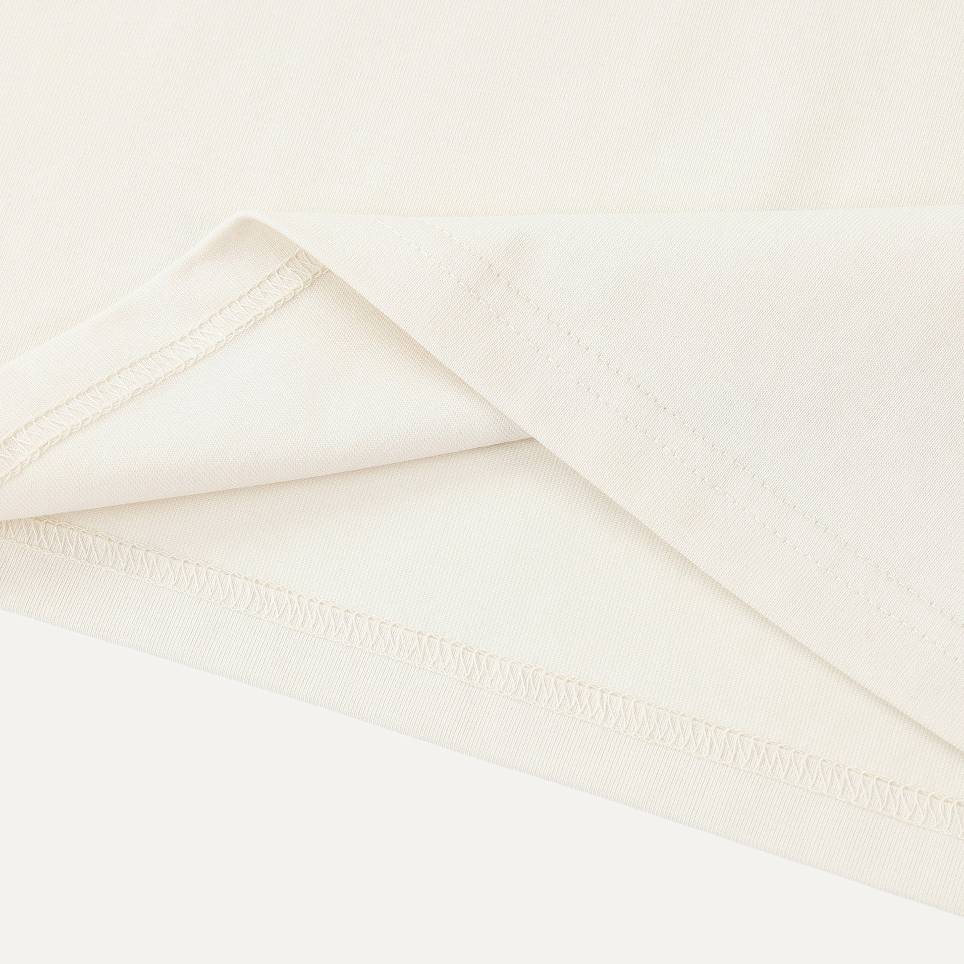Close-up of a folded white fabric with a subtle texture on a light beige background.
