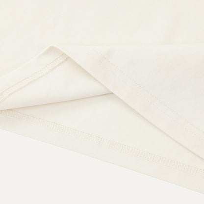 Close-up of a folded white fabric with a subtle texture on a light beige background.