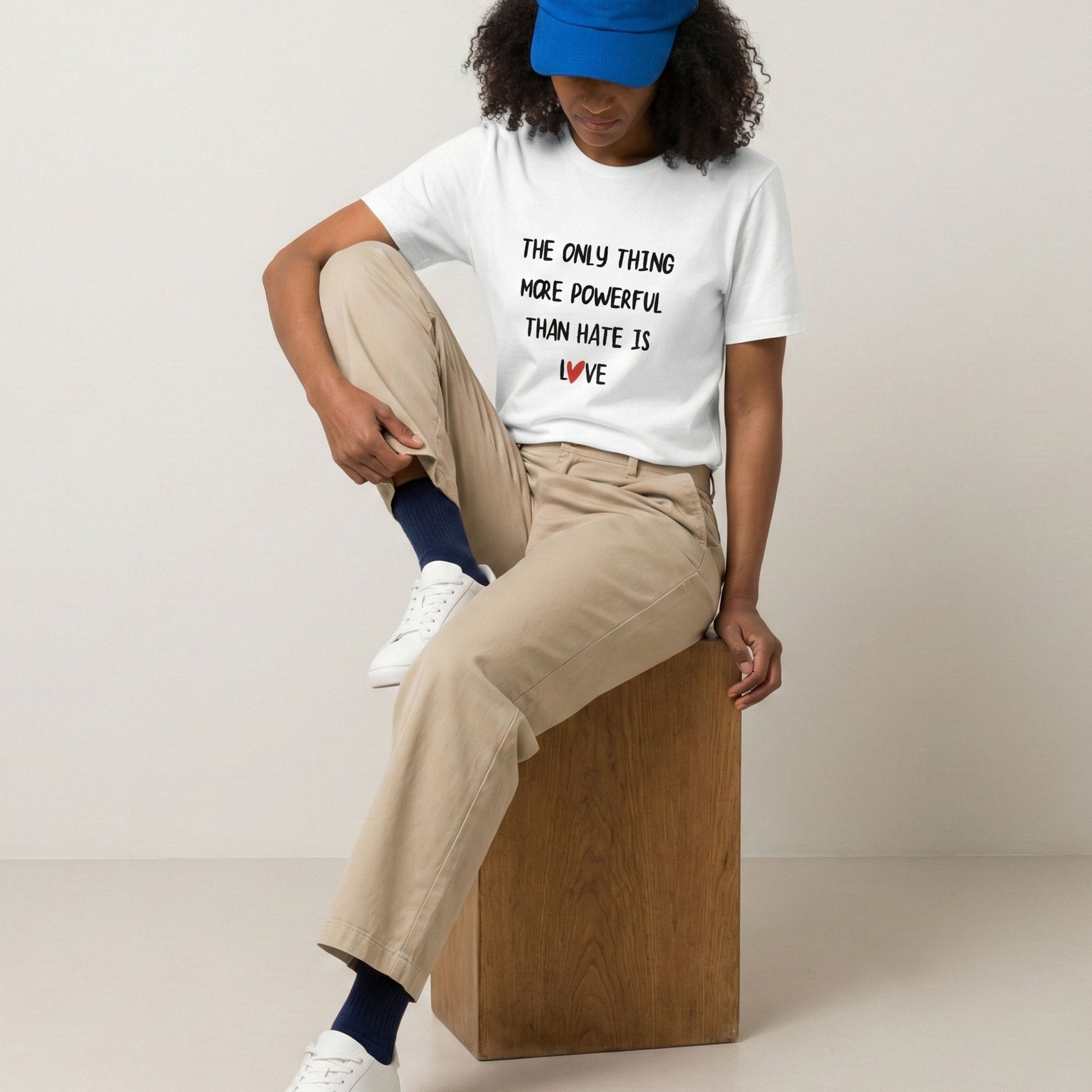 Person wearing a white t-shirt with a message, sitting on a wooden block against a plain background
