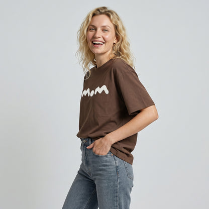 Woman wearing a brown t-shirt with a logo on a plain background
