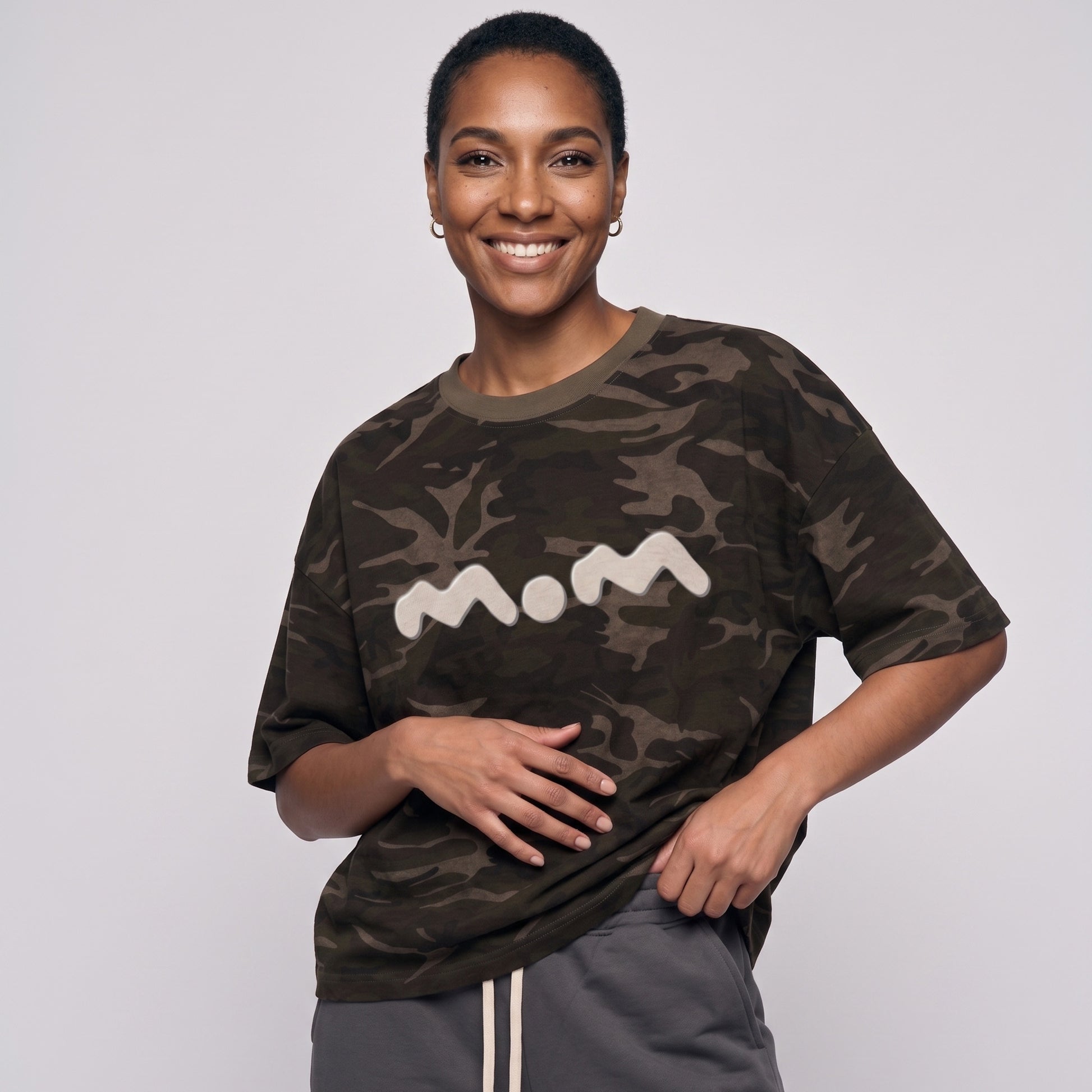 Person wearing a camouflage t-shirt with 'mom' printed on it against a plain background