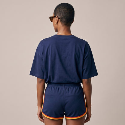 Person wearing a navy blue outfit with shorts on a beige background