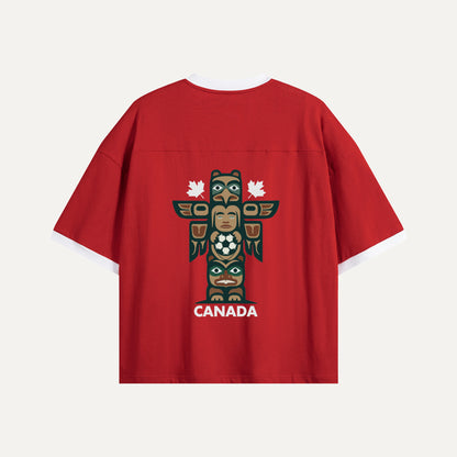 Flat lay of the back of a red Gallery of Nations jersey featuring a detailed totem pole graphic holding a soccer ball, flanked by two white maple leaves.