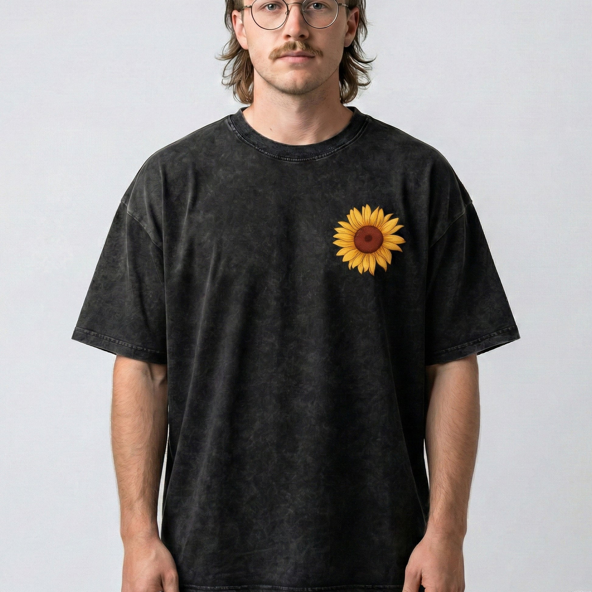 Person wearing a black t-shirt with a sunflower design on a plain background