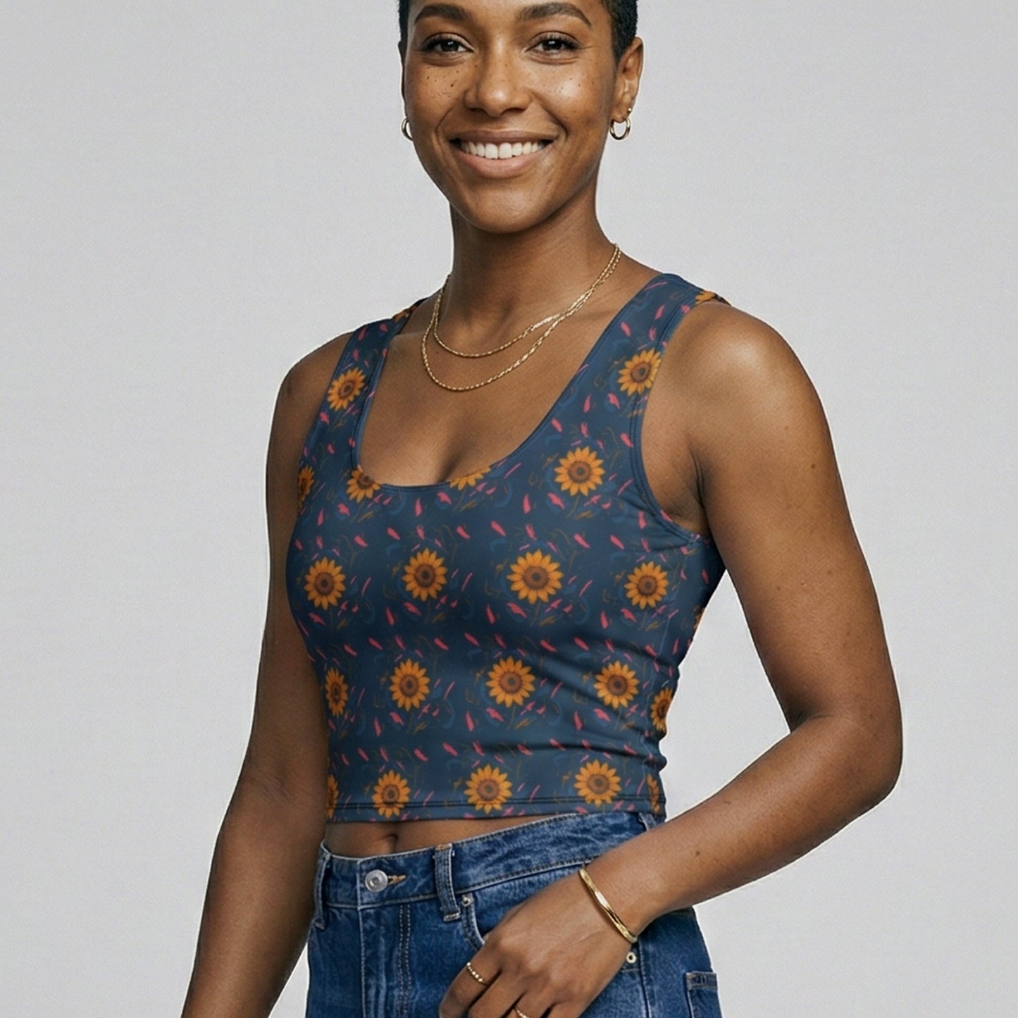 Woman wearing a patterned top and jeans on a plain background