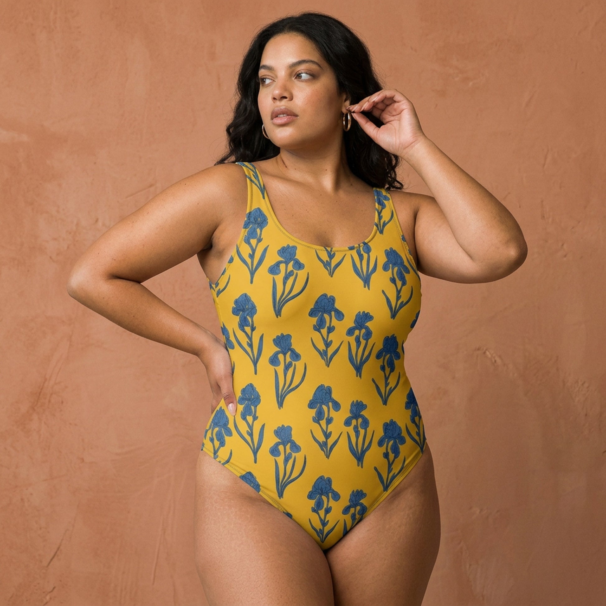 Woman wearing a yellow swimsuit with blue floral patterns against a brown background