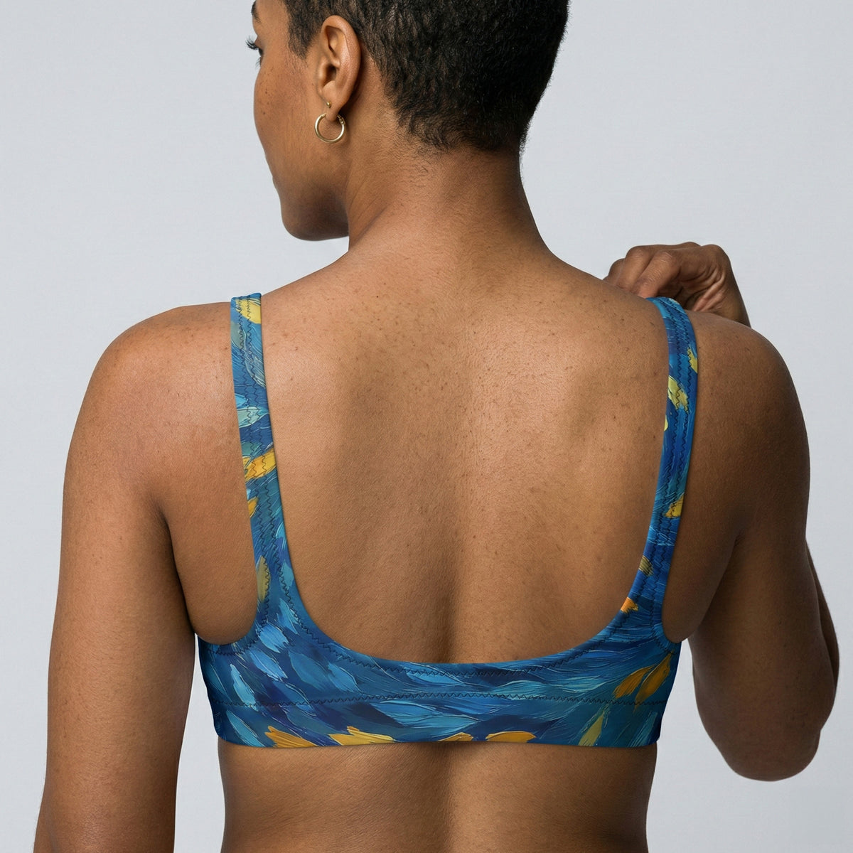 Woman wearing a blue patterned sports bra against a plain background.
