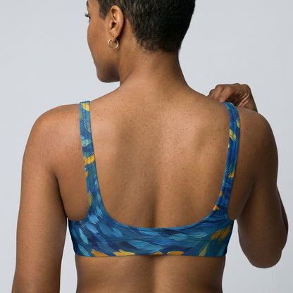 Woman wearing a blue patterned sports bra against a plain background.