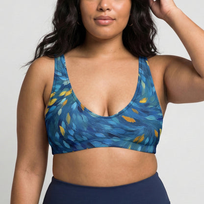 Woman wearing a blue patterned sports bra and navy leggings on a light gray background