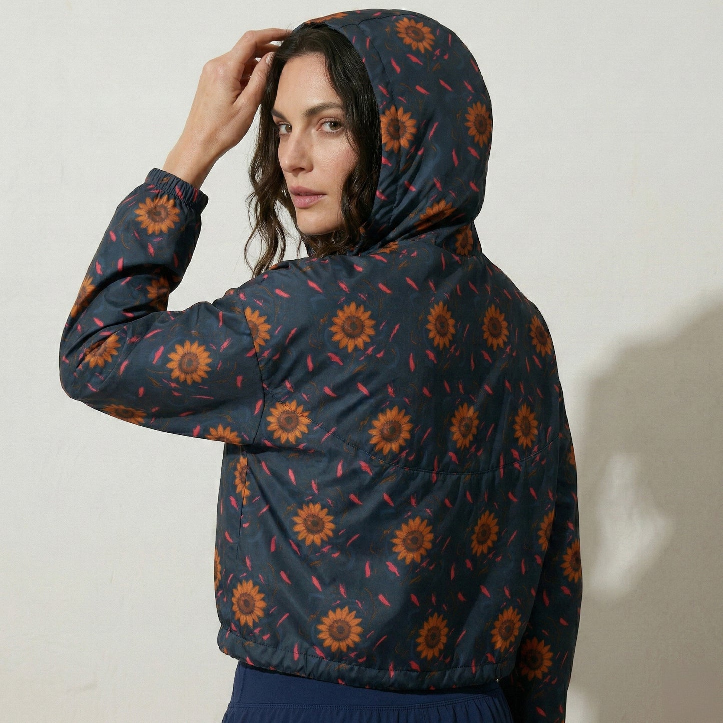 Woman wearing a dark blue jacket with sunflower pattern against a plain background