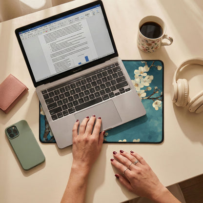 Person using a laptop on a desk with a phone, coffee cup, and headphones nearby.