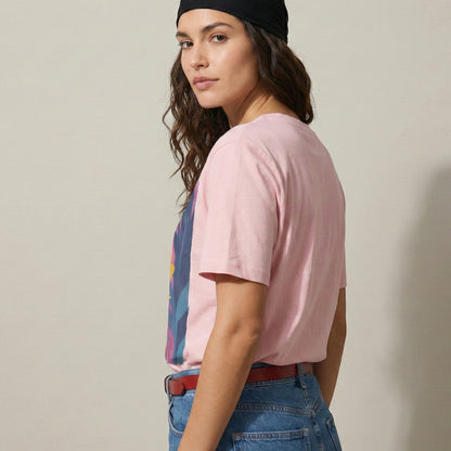 Woman wearing a pink t-shirt with a colorful graphic, blue jeans, and a black headband against a beige background.