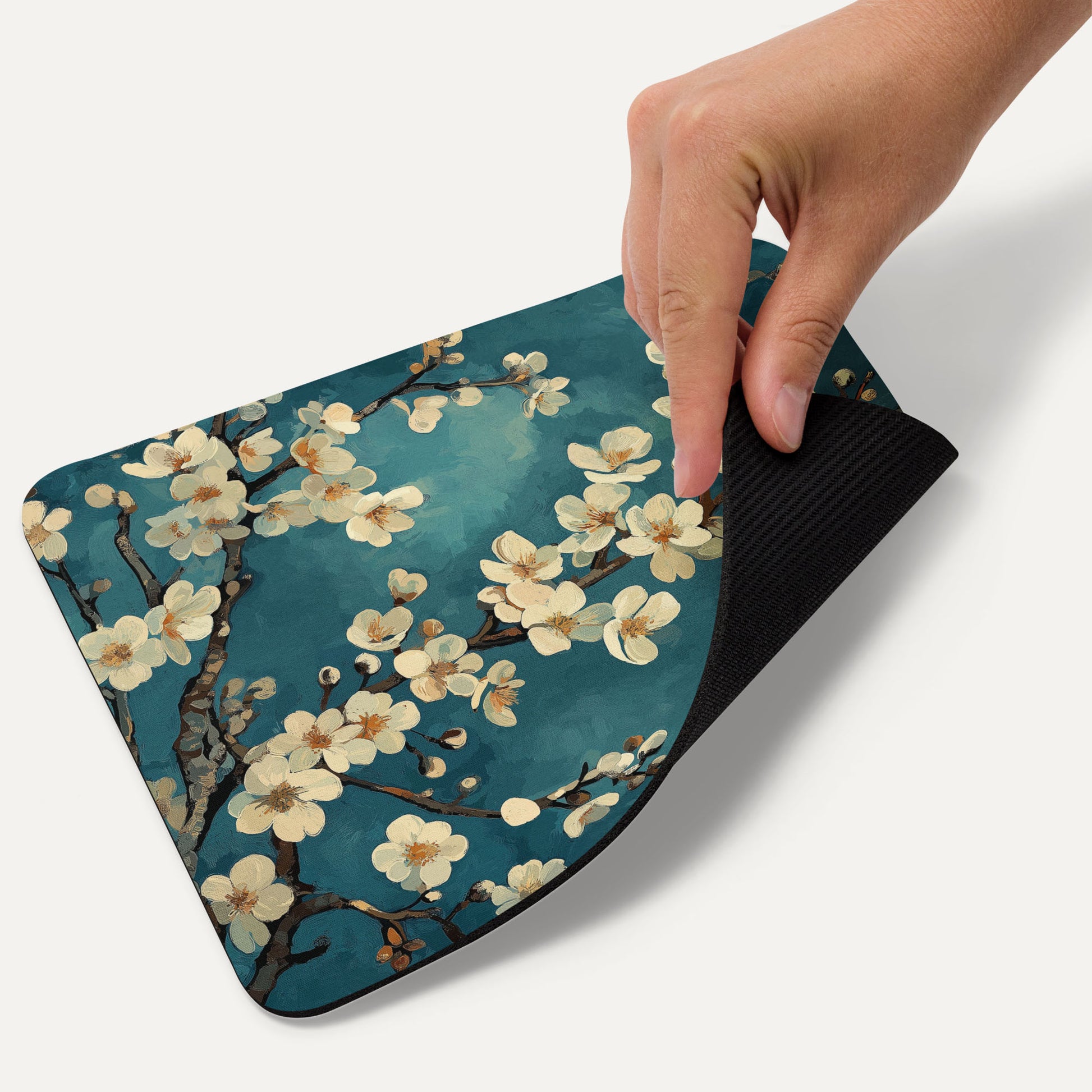 Hand holding a floral mouse pad with cherry blossoms on a blue background