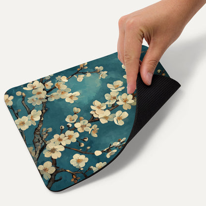 Hand holding a floral mouse pad with cherry blossoms on a blue background